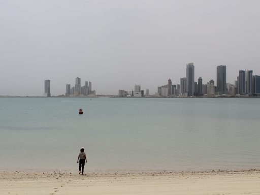 student standing on beach with skyline in background