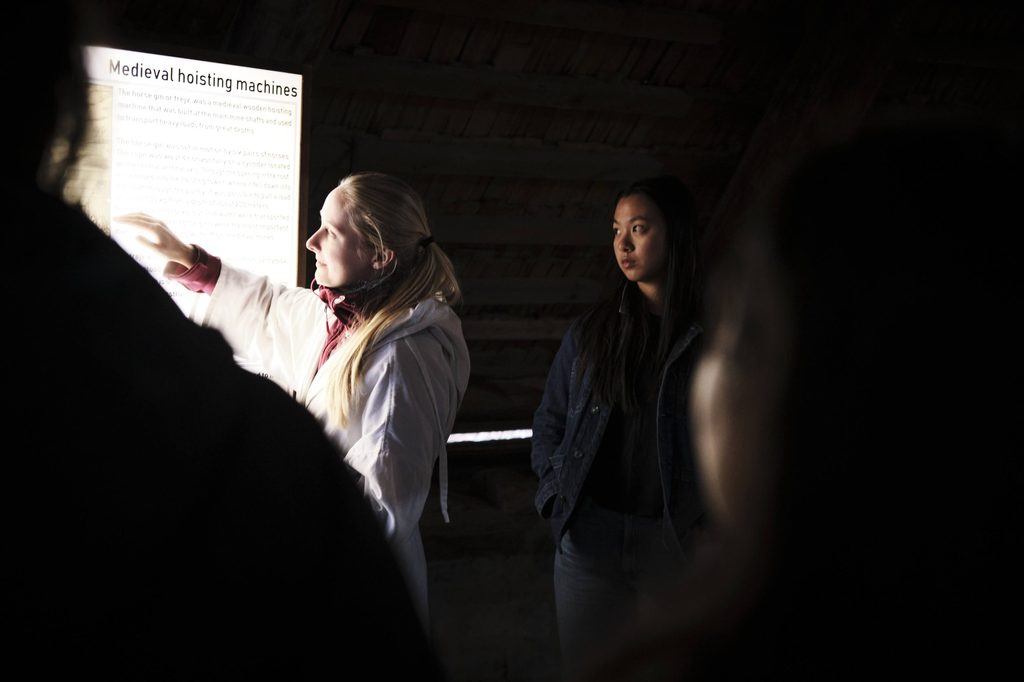 woman pointing at glowing screen with students watching in kutan hora mine
