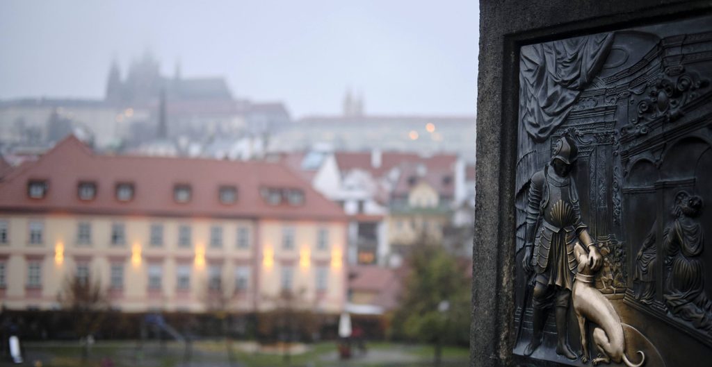 snowy dawn in prague with a bronze carving in forefront 