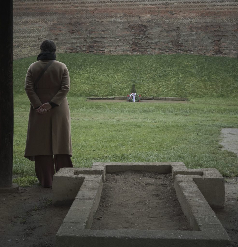 person looking over graves in terezin prison