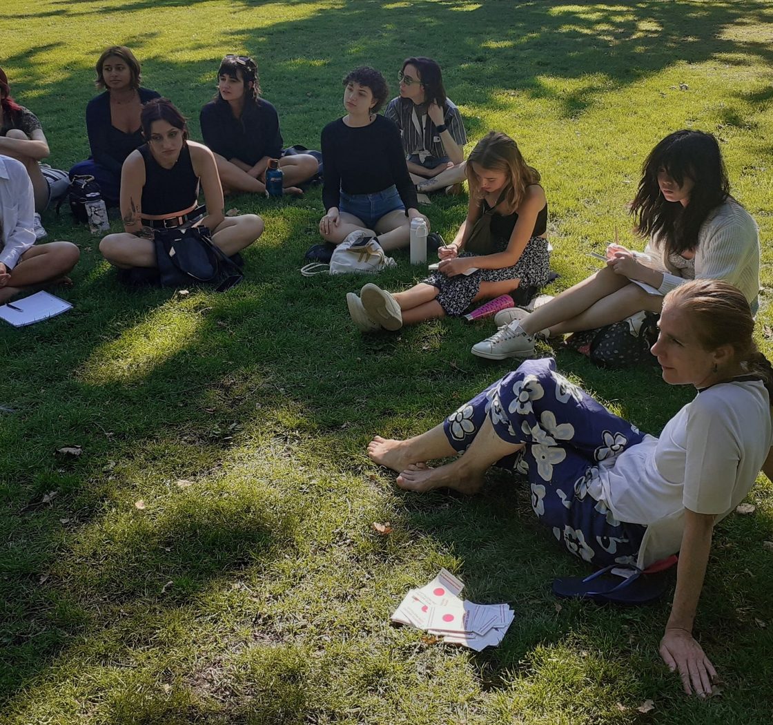 students sit on grass in a circle