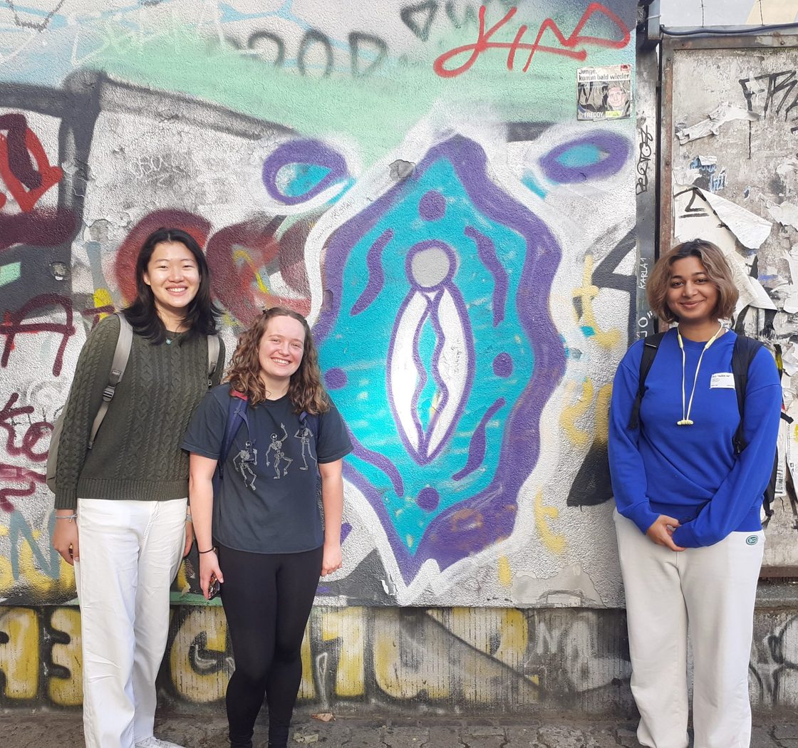 students pose in front of painted walls