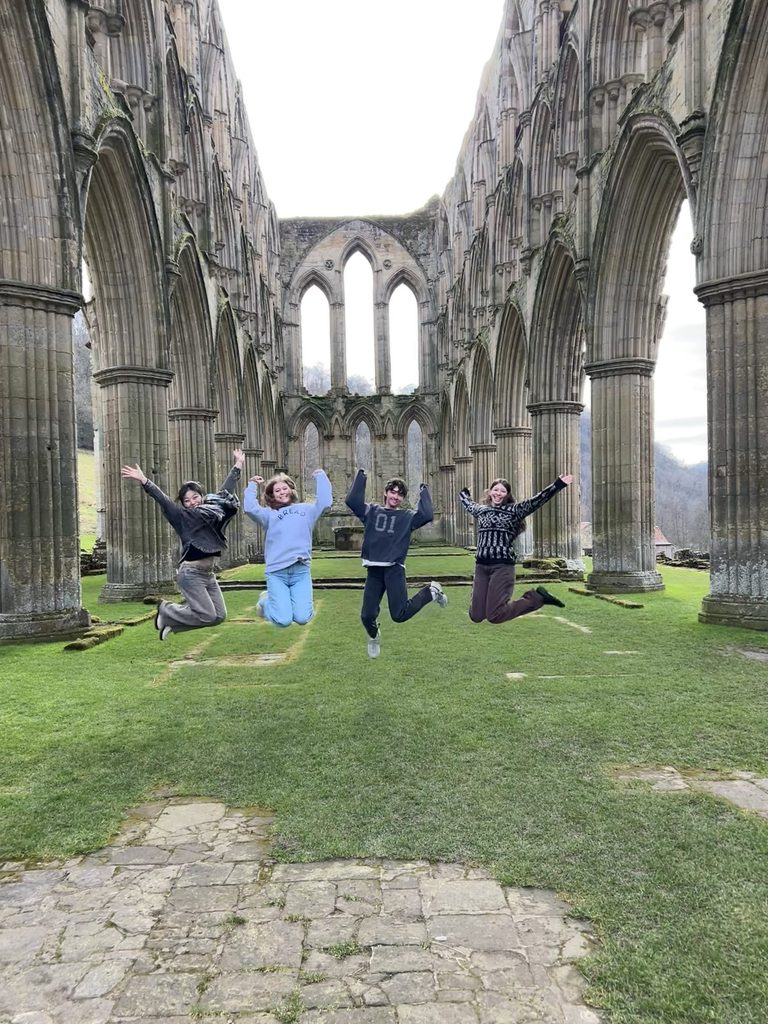 Four students jump in front of some ruins
