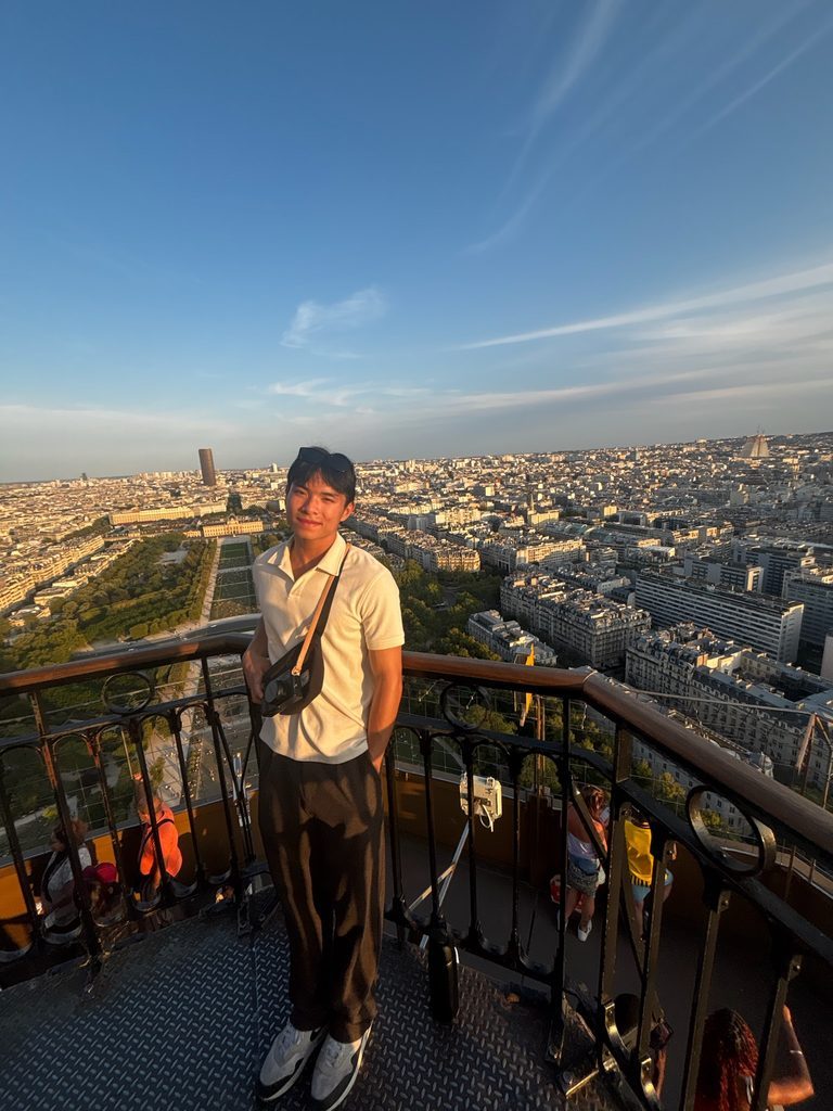 Student poses on top of the eiffel tower