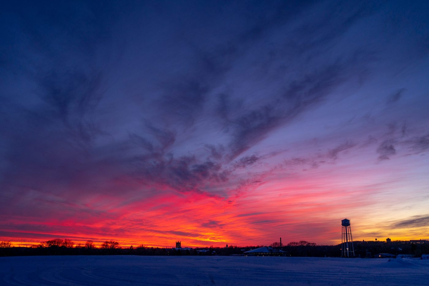 Colorful winter sunset overlooking a field with the Carleton water town and Skinner chapel peaking in the distance