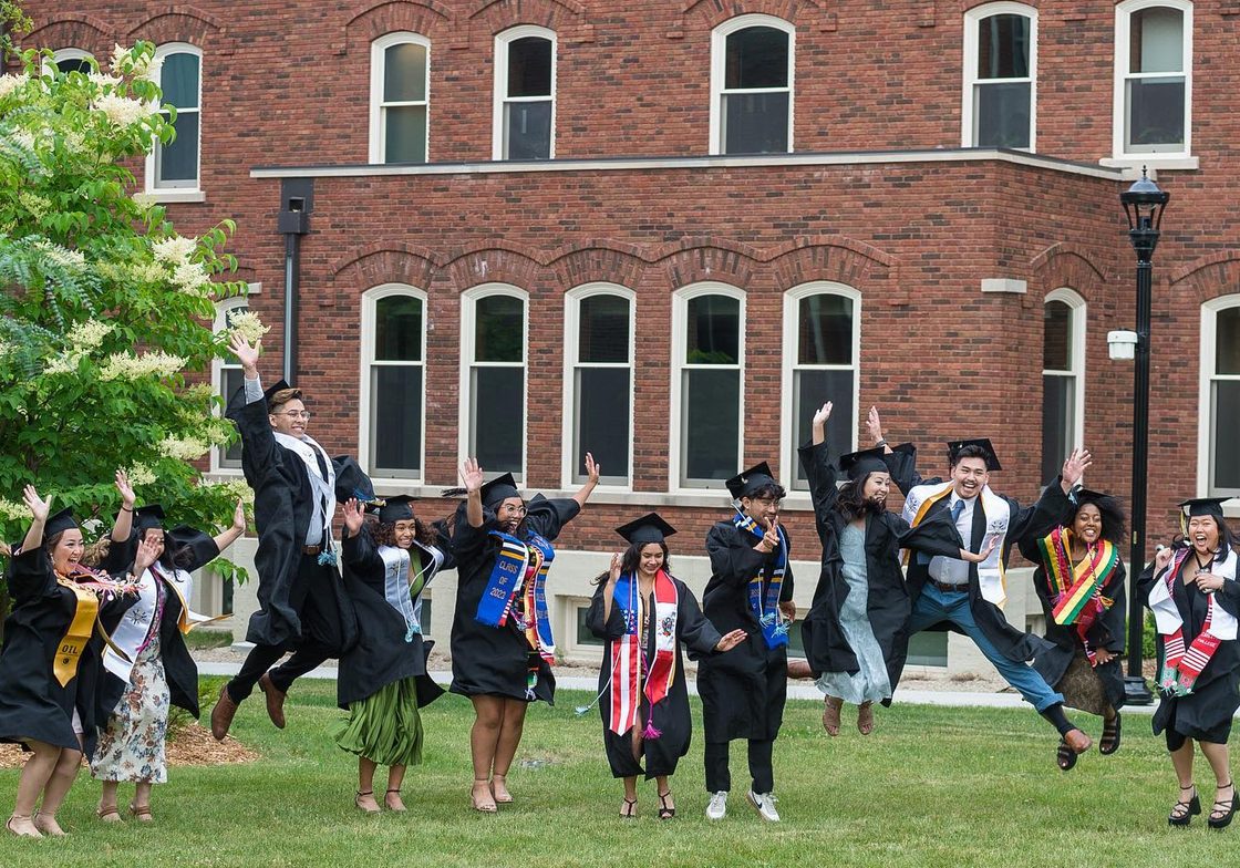 Members of the Class of 2023 jump for joy in their graduation caps and gowns