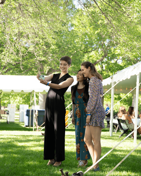 Three members of the Class of 2022 take a selfie in front of the tent