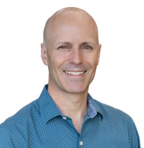 Photo of a person against a white background wearing a blue collared shirt