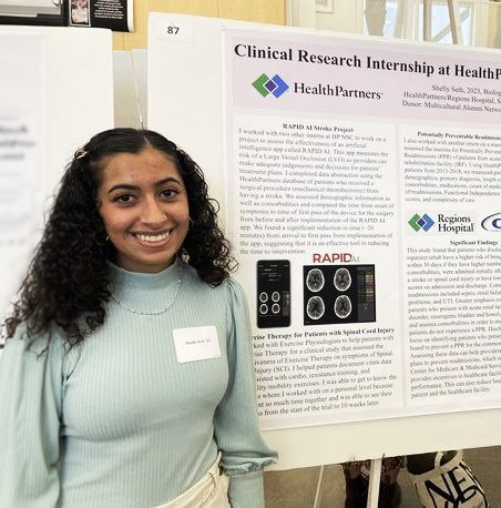 Shelly Seth '23 poses in front of an academic poster titled "Clinical Research Intership at HealthPartners Neuroscience Center"