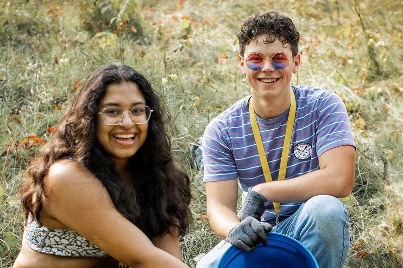 Two students work together planting trees in the Carleton Arboretum