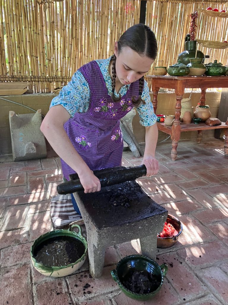 A student makes mole, she is grinding the toasted hot peppers into a paste using a traditional metate made of volcanic stone. We all took turns grinding it because it was a large batch. Mole is a sauce made of over 35 ingredients that are toasted and then ground together; it features different hot peppers, roasted tomatoes and other veggies, chocolate, cinnamon, herbs and more!