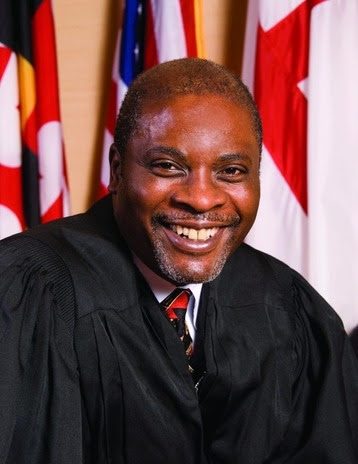 Judge in robes with flags in the background