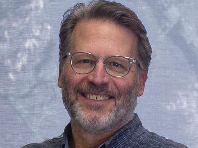 Photo of a person with glasses wearing a gray collared shirt.