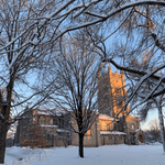 Snow covered trees before a sun-lit chapel