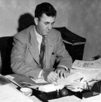 Black and White photo of Laurence McKinley Gould seated at a desk with books