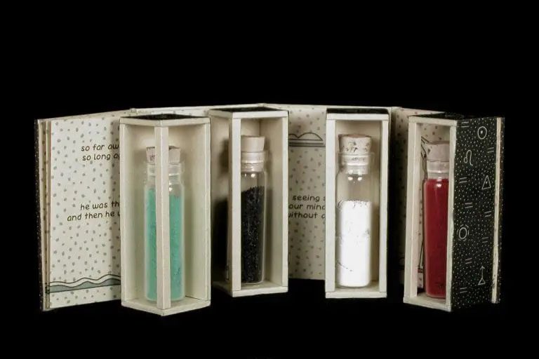 Jody Williams' book "For Now" shown open, revealing four vials of different colored sand