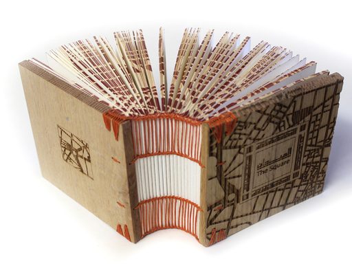 An image of an artist's book with square covers and hand sewn binding, with a laser-etched map of Cairo on the cover
