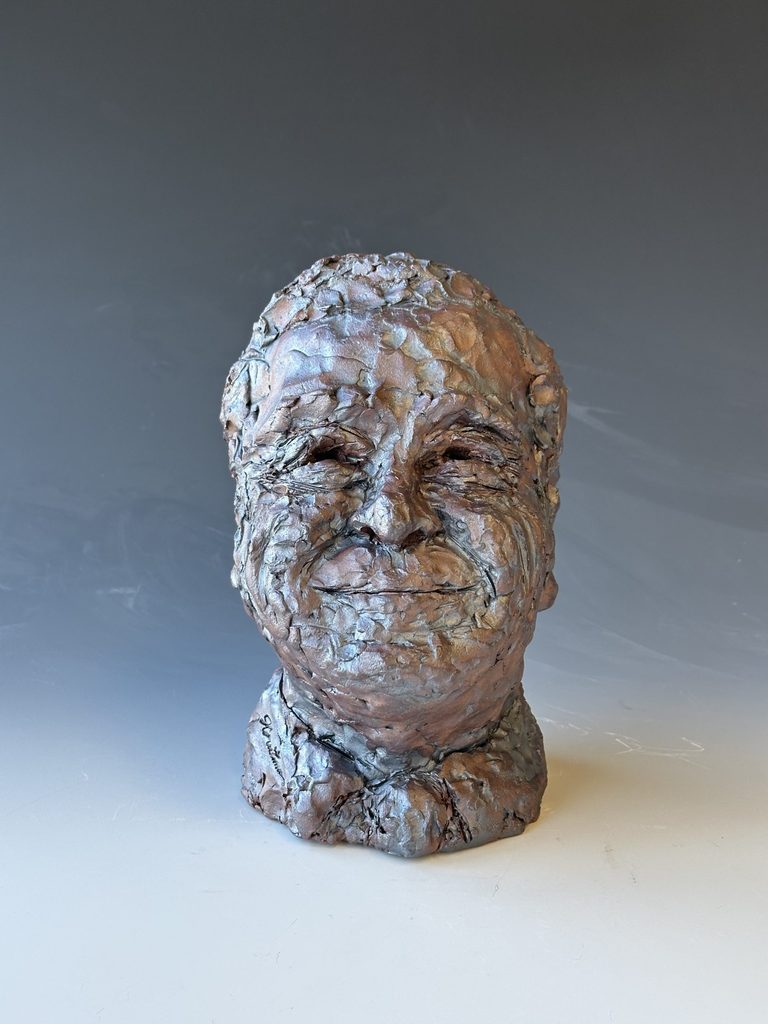 a bust of Steven Poskanzer sculpted from clay on a gray and white background