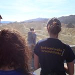 Students listening to instructor in front of ridges in desert