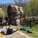 Students gathered around large rock formation, observing it