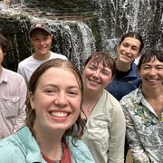 Students and faculty member stand in front of a waterfall.