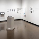 A series of comic-book illustrations, including pages of a comic book, portraits of characters, a pillar on which a stack of free comic books are placed, and a corner that says “Draw Something Here!” upon which visitors have doodled.