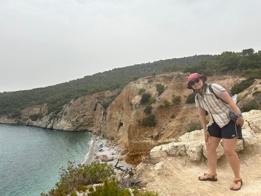 Stella stands on a clif overlooking a pebble beach on Agistri