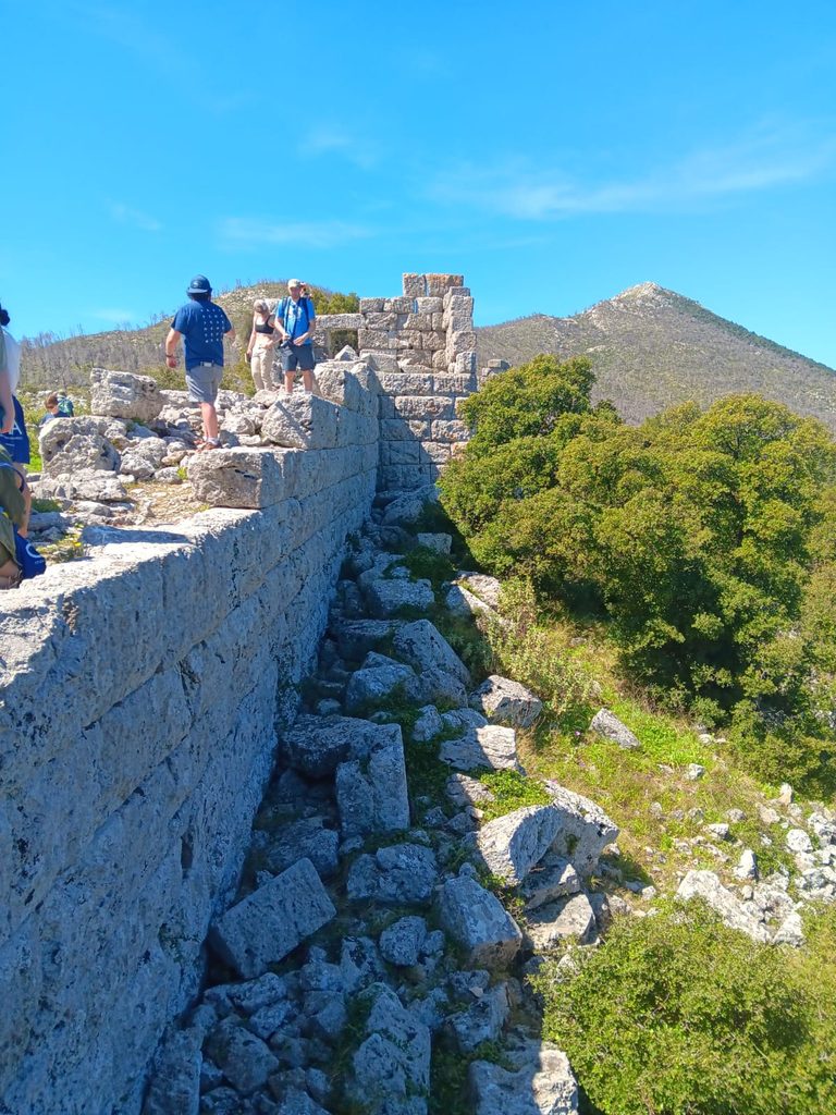 A view of the walls and towers of the Elutherai forterss. Some students are climbing on top of it.