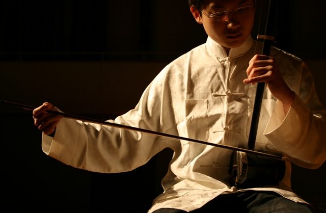 Photo of a young man playing a traditional Chinese stringed instrument