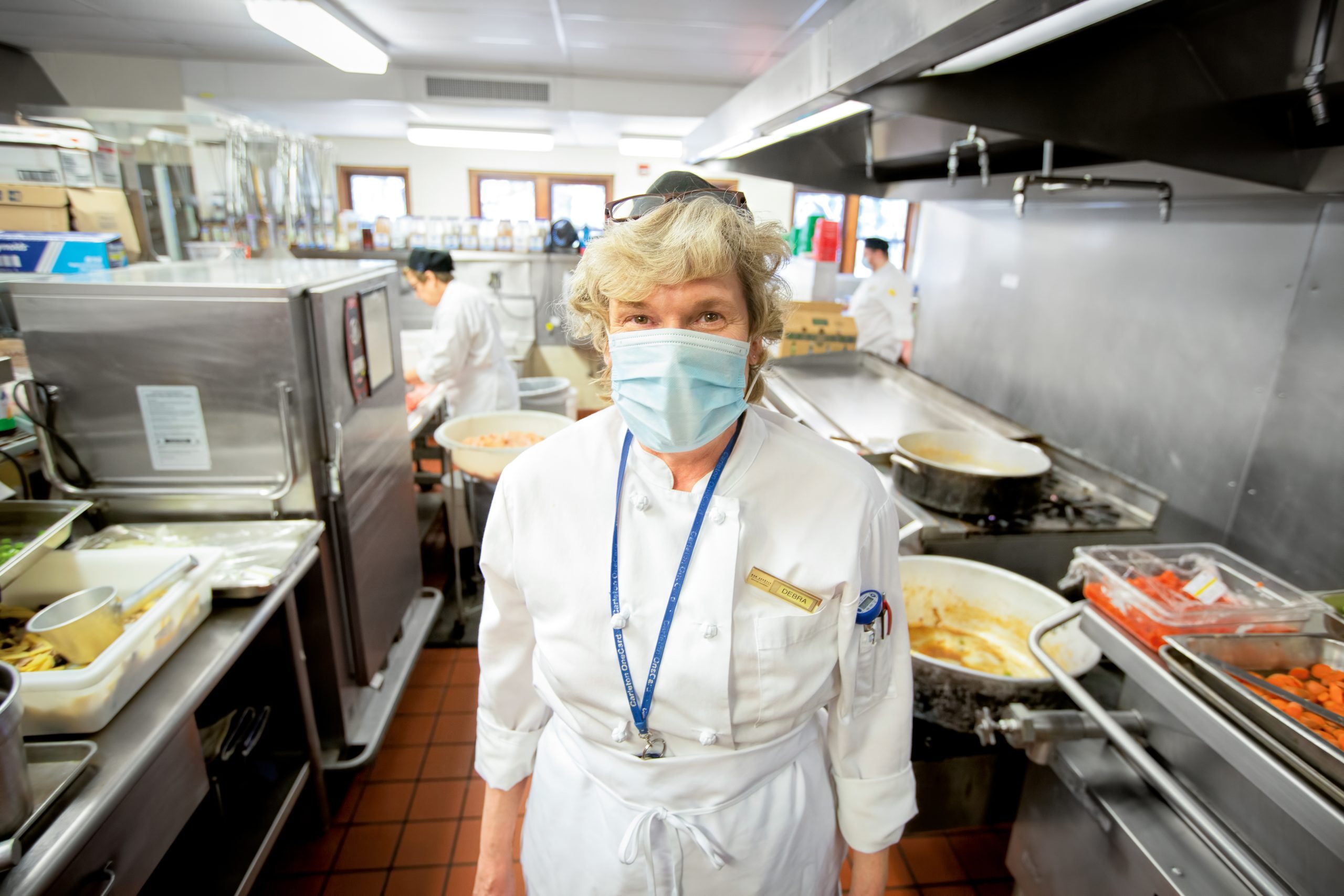 Burton cook Deb Swanson prepares lunch while staying at least six feet away from her colleagues.