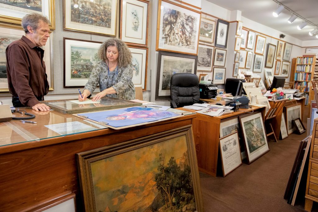 Lisa Jane Toczek surrounded by framed prints and paintings