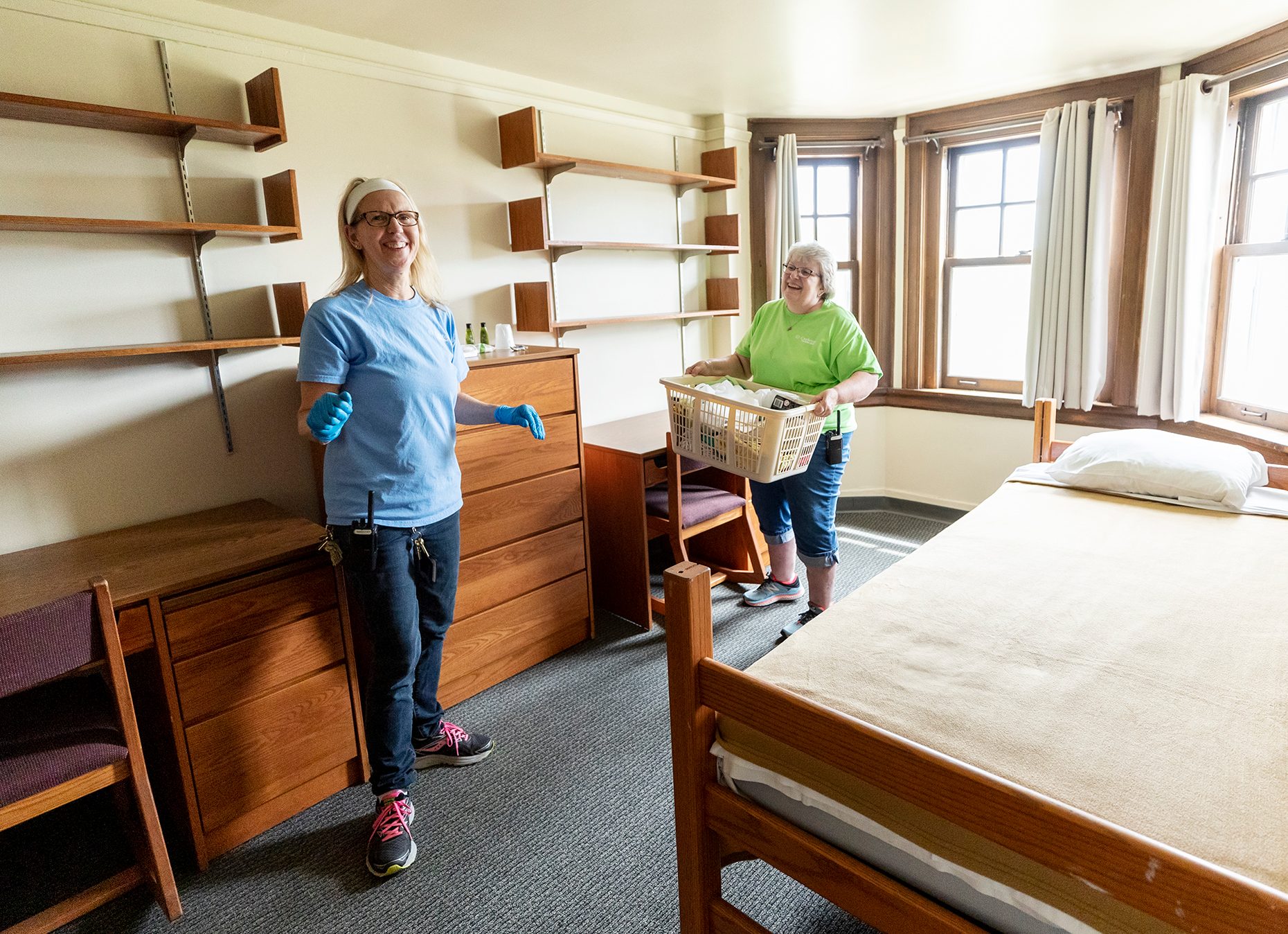 Custodians clean a dorm room in preparation for reunion