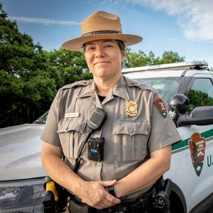 Deputy Chief Ranger Therese Picard stands next to her patrol car during her morning shift at Schooner Head Overlook in Acadia National Park, ME