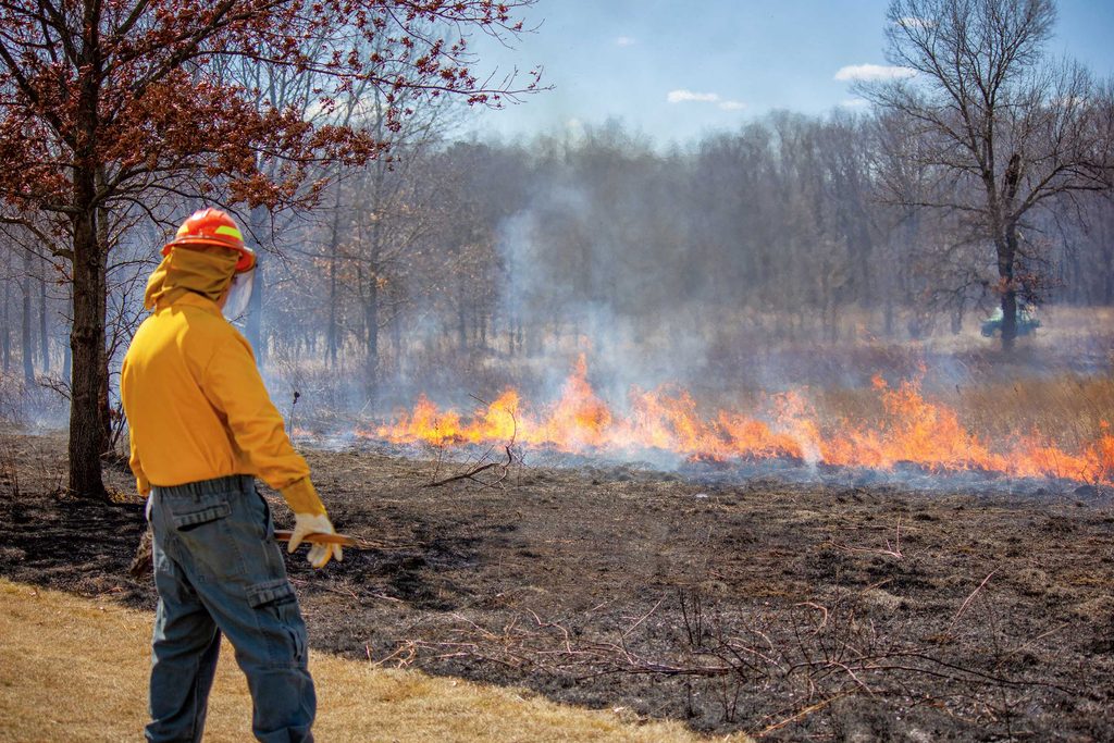 firefighter watches over a controlled burn in the prairie