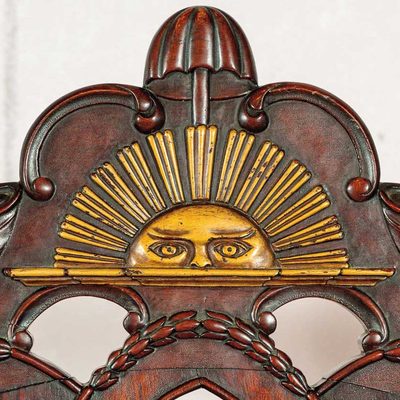 a golden sun rising or setting on a mahogany chair back