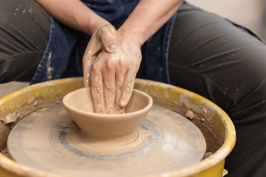 close up of hands throwing pottery