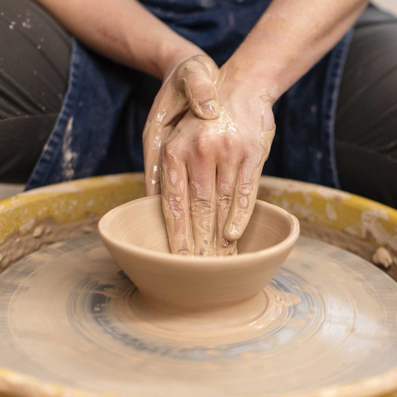 close up of hands throwing a bowl on a pottery wheel