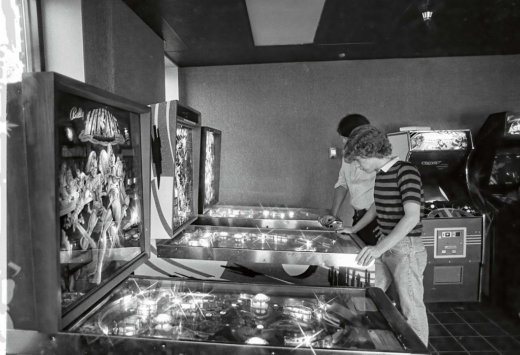 vintage photo of young student playing on a pinball machine