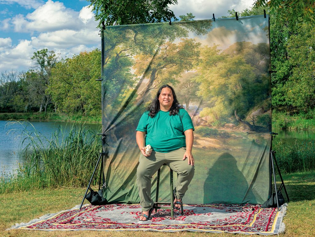 Roger Faust poses outdoors with a backdrop and the skull of a wolf
