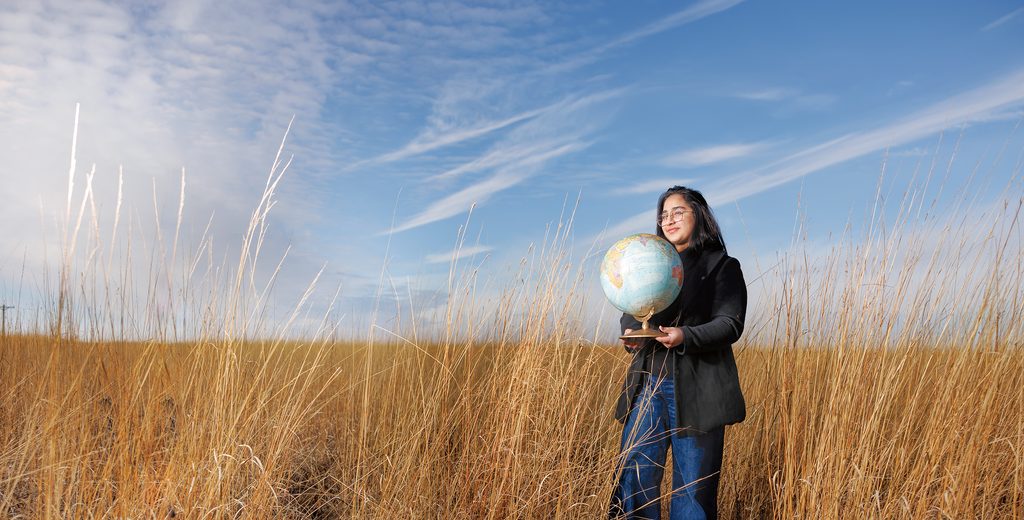 Zainab Waheed holding a globe standing in the arb