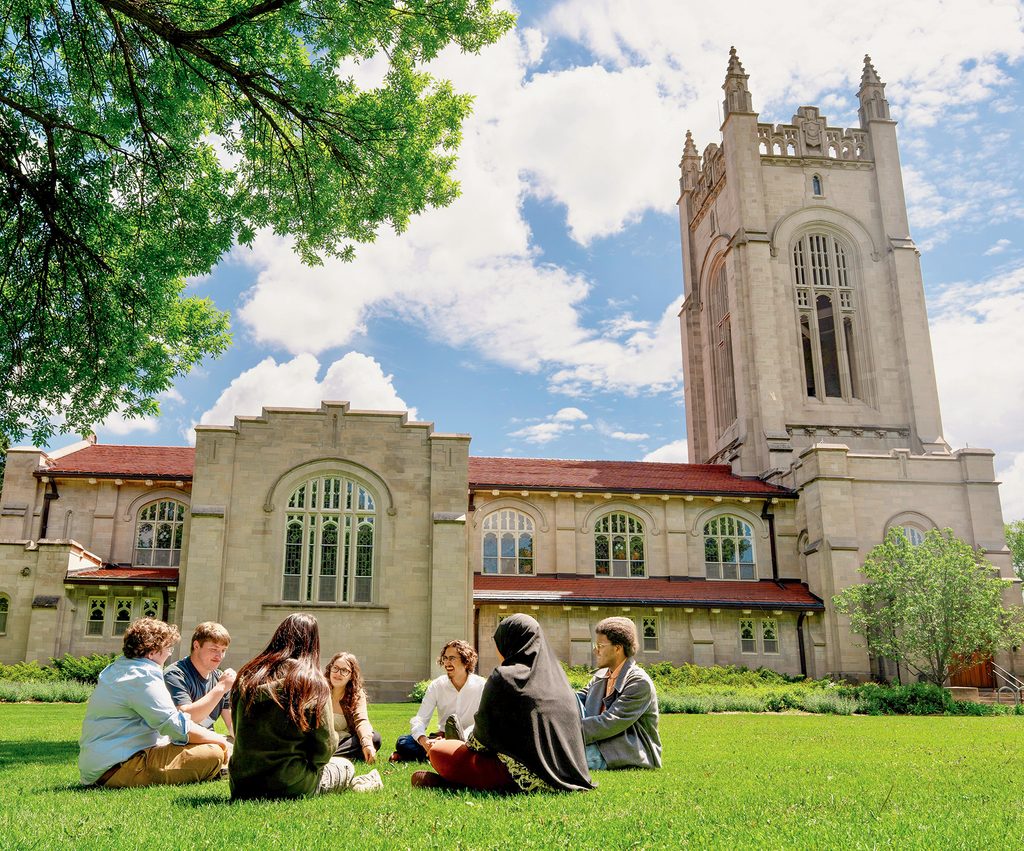 students seated on the grass outside skinner memorial chapel