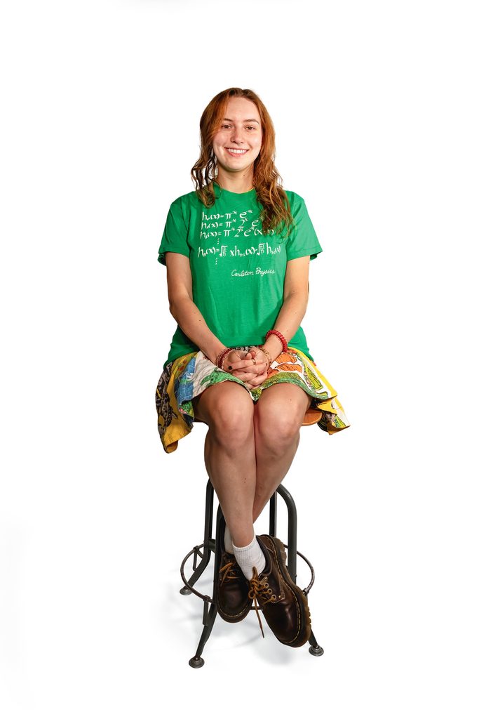 student seated modeling a green department tshirt