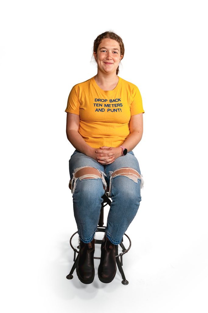 student seated wearing yellow Metric Football Game tshirt