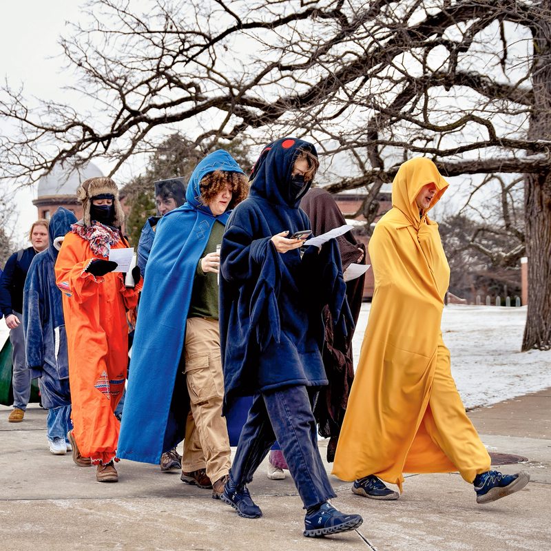 Students in colorful robes take part in a search for Schiller challenge