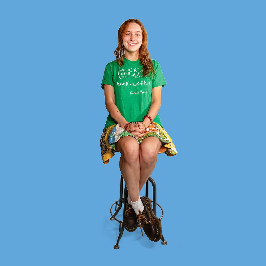 student seated wearing a green physics department tshirt