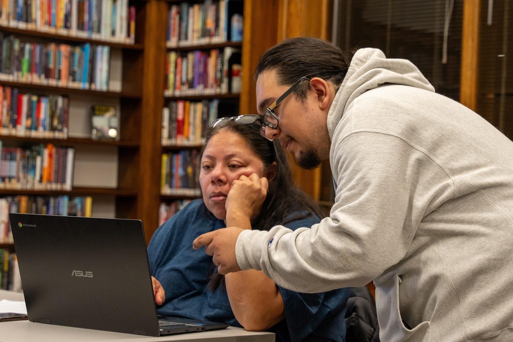 A carleton student helps a patron with her computer at the Northfield Public Library