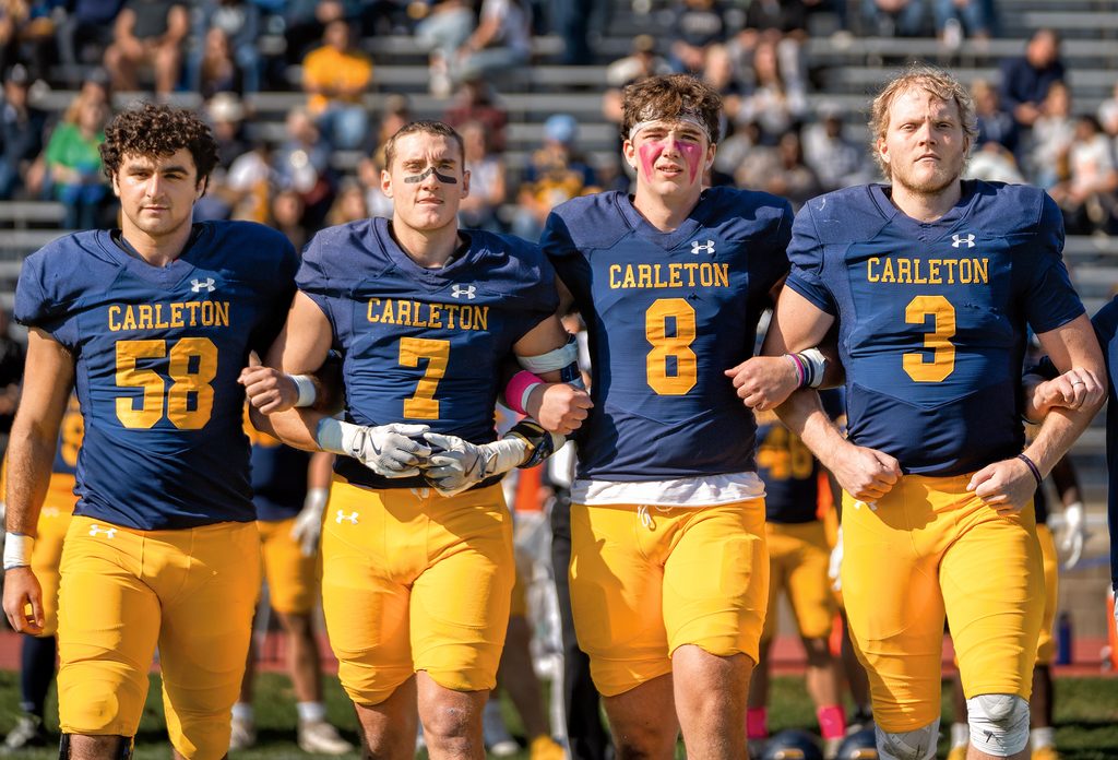 Four Carleton football players link arms and look tough