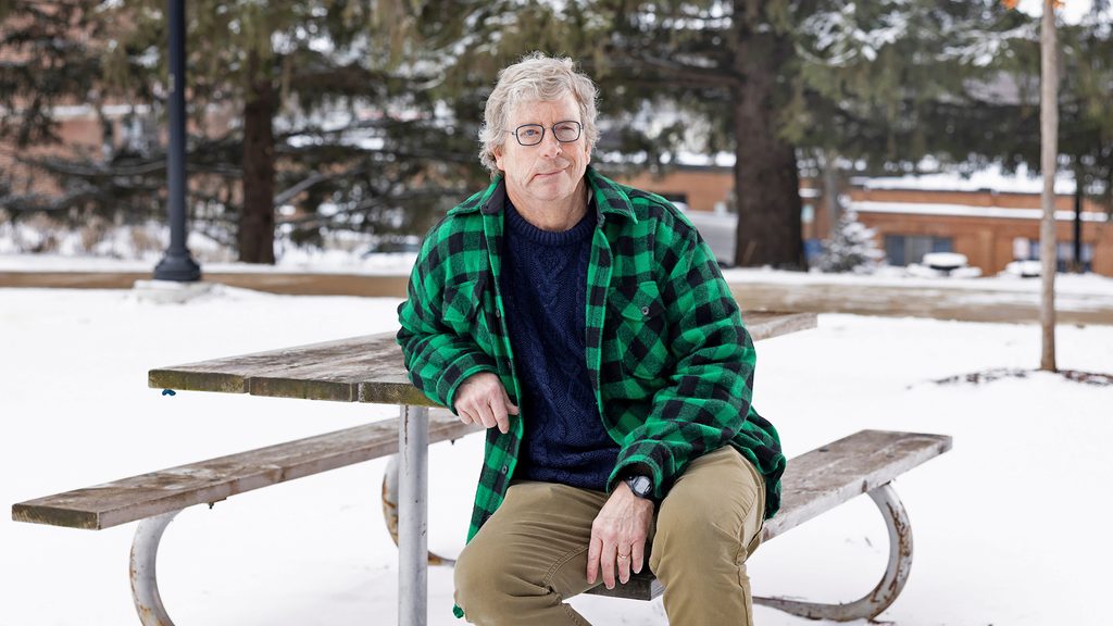 Michael McNally sits at a picnic table on a snowy day