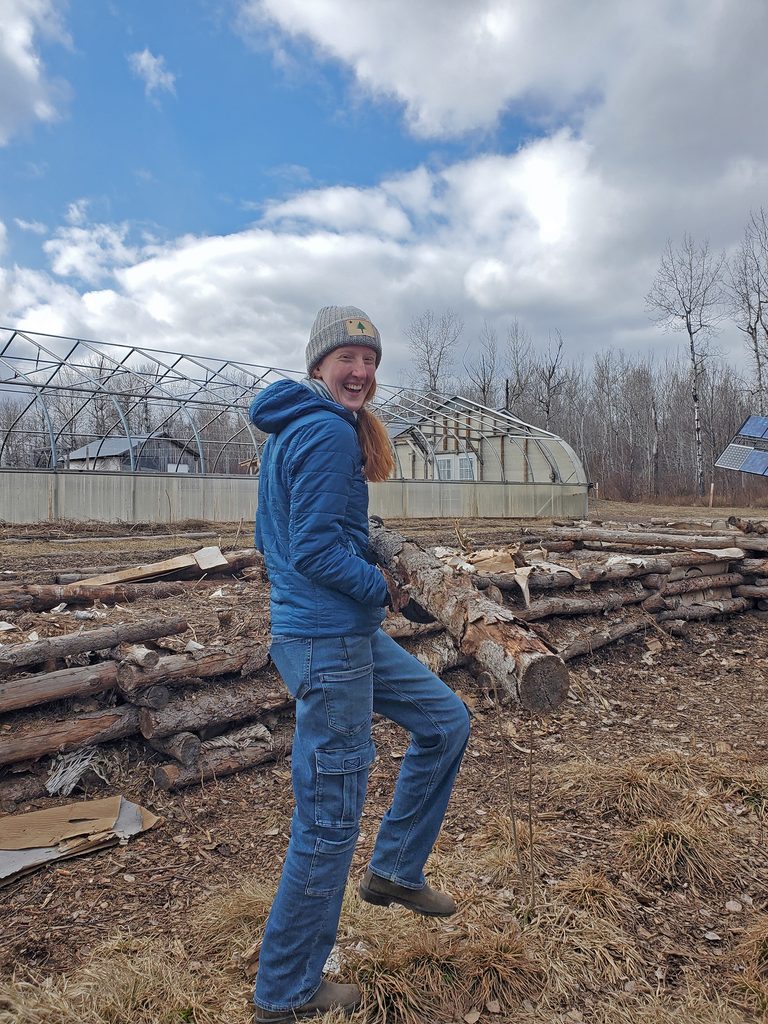 Carleton student Moriah Reusch carries a log on a cloudy early spring day
