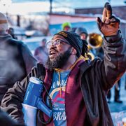 A man with a megaphone leads a brass band on a winter street
